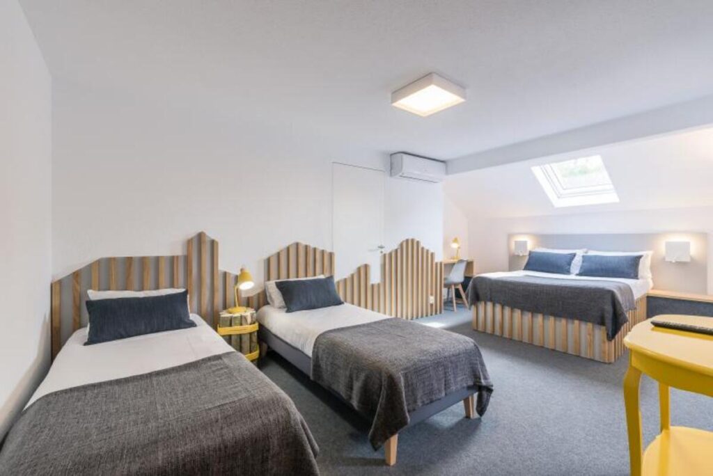 Une chambre de l'hôtel avec deux lits simples et un lit double
